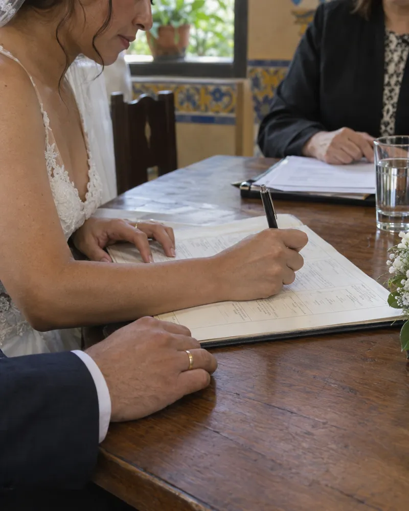 Novios firmando el acta de matrimonio civil sobre una mesa con flores